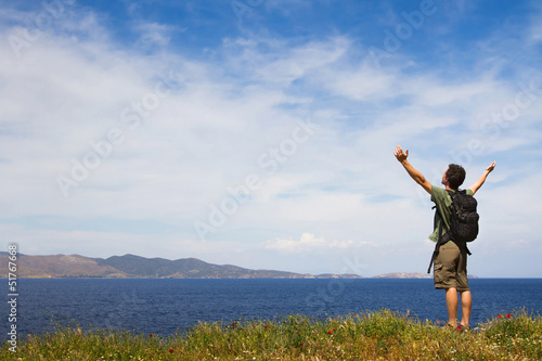 Photo: Young tourist with backpack enjoying sea view from top of a hill Young tourist with backpack enjoying sea view from top of a hill