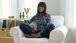 Happy African American woman sitting cross legged on couch