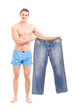 Full length portrait of  a fit muscular man holding a pair of je