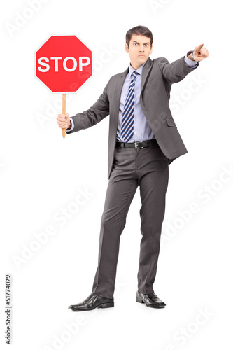Photo: Full length portrait of a man in suit holding a stop sign Full length portrait of a man in suit holding a stop sign