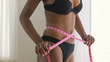 Healthy Black woman measuring waist on diet