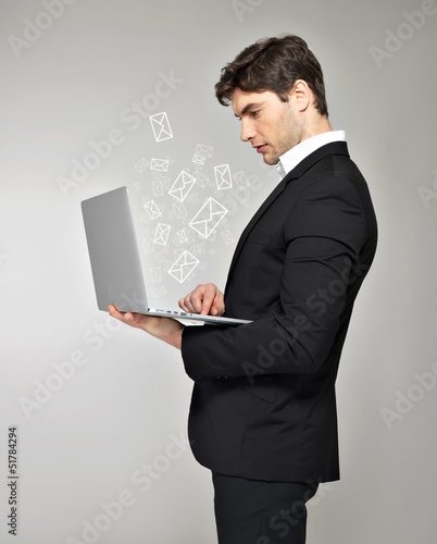Photo: Business man with laptop and mail icon Business man with laptop and mail icon