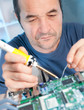 Senior tech fixes computer circuit board