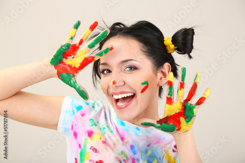 Photo: Young pretty painter with hands in paint, on gray background Young pretty painter with hands in paint, on gray background