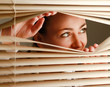 Portrait of a woman looking through out the blinds