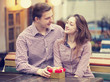 Photo: The young man gives a gift to a young girl in the cafe and they The young man gives a gift to a young girl in the cafe and they