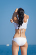 Attractive brunette in white swimwear undressing on the beach
