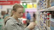 Young woman is choosing food for her child in the supermarket.