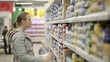 Young woman is choosing food for her child in the supermarket.