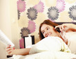 A teenager girl lying on a bed reading a book