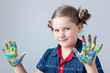 Photo: Beautiful little girl showing painted hands over grey background Beautiful little girl showing painted hands over grey background