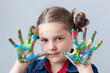Photo: Beautiful little girl showing painted hands over grey background Beautiful little girl showing painted hands over grey background