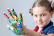 Photo: Beautiful little girl showing painted hands over grey background Beautiful little girl showing painted hands over grey background
