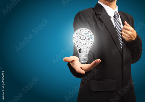 Photo: Business man holding Light bulb with drawing graph inside Business man holding Light bulb with drawing graph inside