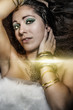 sexy brunette young woman lying with golden jewelry, gold