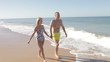 Senior Couple Holding Hands Walking Along Beach