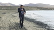 Young businessman jogging on the seashore with cellphone, slow m