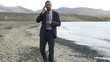 Young businessman standing on the seashore with cellphone, slow 