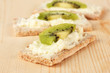 Tasty canapes with cheese and kiwi, on wooden background