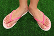 Photo: Beautiful woman legs in summer slippers on green grass Beautiful woman legs in summer slippers on green grass