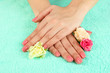 Foto: Woman hands with pink manicure and flowers, on color background Woman hands with pink manicure and flowers, on color background