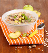 Useful oatmeal in bowl with fruit on wooden table close-up