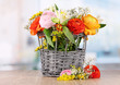 Many different flowers in basket on room background