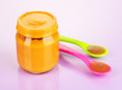 Baby food with weaning spoons on purple background