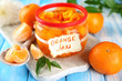 Orange jam with zest and tangerines, on blue wooden table