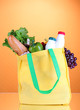Eco bag with shopping on orange background