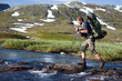 Wanderer beim überqueren von Stromschnellen in Norwegen