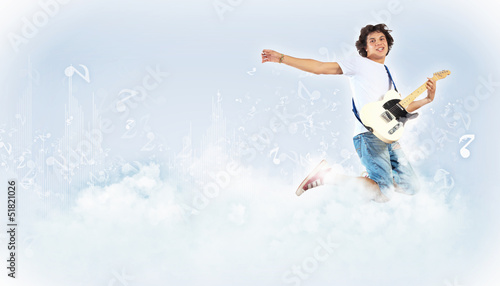 Photo: young man playing on electro guitar and jumping young man playing on electro guitar and jumping