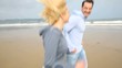 Cheerful woman running with husband on the beach