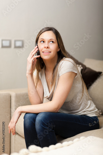 Photo: Woman using a cell phone while relaxing on a couch Woman using a cell phone while relaxing on a couch