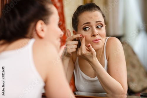 Photo: .Woman finding an acne on her cheek .Woman finding an acne on her cheek