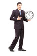 Full length portrait of a youn man in suit pointing on a clock