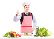 Man with apron posing with vegetables and giving a thumb up