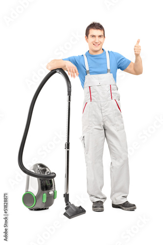 Photo: Full length portrait of a male cleaner with a vacuum cleaner giv Full length portrait of a male cleaner with a vacuum cleaner giv