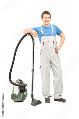 Photo: Full length portrait of a man in uniform posing with a vacuum cl Full length portrait of a man in uniform posing with a vacuum cl
