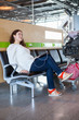 Photo: Woman dreaming with pc in airport lounge with luggage cart Woman dreaming with pc in airport lounge with luggage cart