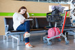 Photo: Young woman sitting with luggage hand-cart in airport lounge Young woman sitting with luggage hand-cart in airport lounge
