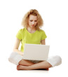 Photo: A young girl sitting on the floor with a laptop A young girl sitting on the floor with a laptop