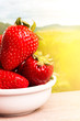 Strawberries in white plate on wooden table. Country background