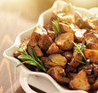 rosemary herb potatoes in white baking dish close up up.