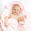 Foto: Caucasian baby boy covered with pink towel joyfully smiles at ca Caucasian baby boy covered with pink towel joyfully smiles at ca