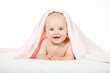 Foto: Caucasian baby boy covered with pink towel joyfully smiles at ca Caucasian baby boy covered with pink towel joyfully smiles at ca