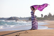 Woman stands at seashore and waves with her pareo