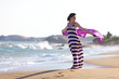 Woman stands at seashore and waves with her pareo