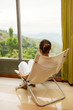 Photo: Woman is sitting in cozy armchair at hotel high up in mountains Woman is sitting in cozy armchair at hotel high up in mountains