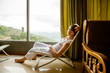 Photo: Woman is sitting in cozy armchair at hotel high up in mountains Woman is sitting in cozy armchair at hotel high up in mountains
